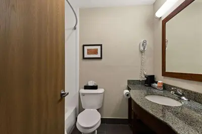 a bathroom with a toilet and a sink and a mirror at Comfort Inn Huntington Near University in Huntington
