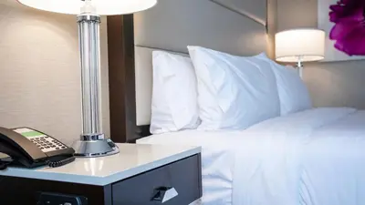 a hotel room with a phone next to a bed at Holiday Inn Wilmington by IHG in Gurneyville