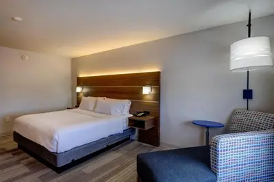 a hotel room with a bed and a chair at Holiday Inn Express & Suites Shelbyville Indianapolis by IHG in Shelbyville