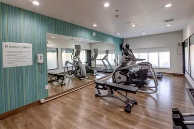 a gym with treadmills and ellipticals in front of a mirror at Holiday Inn Express & Suites Shelbyville Indianapolis by IHG in Shelbyville