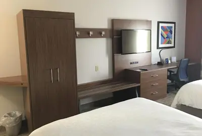 a hotel room with a bed and a desk with a mirror at Holiday Inn Express Greensburg by IHG in Greensburg