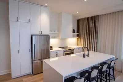 a kitchen with white cabinets and a kitchen island with chairs at Hotel Covington Cincinnati Riverfront in Covington
