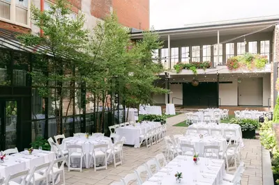 a courtyard with white tables and chairs in front of a building at Hotel Covington Cincinnati Riverfront in Covington