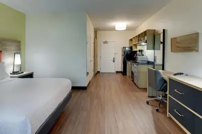 a hotel room with a bed and a desk and a kitchen at Candlewood Suites Lexington by IHG in Lexington