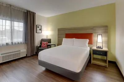 a hotel room with a large bed and a chair at Candlewood Suites Lexington by IHG in Lexington