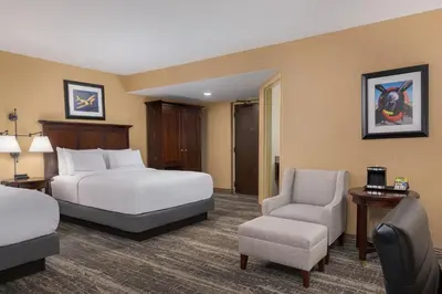 a hotel room with two beds and a chair at DoubleTree by Hilton Cincinnati Airport in Hebron