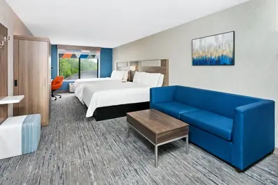 a hotel room with a bed and a blue couch at Holiday Inn Express Hotel & Suites Youngstown - North Lima/Boardman by IHG in North Lima