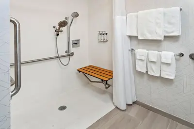 a bathroom with a shower and a bench and towels at Holiday Inn Express Hotel & Suites Youngstown - North Lima/Boardman by IHG in North Lima