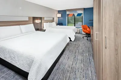 a hotel room with two beds and a chair at Holiday Inn Express Hotel & Suites Youngstown - North Lima/Boardman by IHG in North Lima