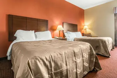 two beds in a hotel room with orange walls at Quality Inn & Suites Lawrenceburg in Lawrenceburg