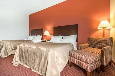 a hotel room with two beds and a chair at Quality Inn & Suites Lawrenceburg in Lawrenceburg