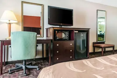 a hotel room with a bed and a television and a chair at Quality Inn & Suites Lawrenceburg in Lawrenceburg