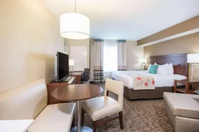 a hotel room with a bed and a living room at Hawthorn Extended Stay by Wyndham Saint Clairsville in Saint Clairsville