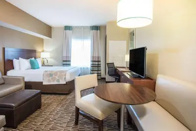 a hotel room with a bed and a living room at Hawthorn Extended Stay by Wyndham Saint Clairsville in Saint Clairsville