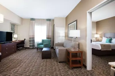 a hotel room with a bed and a living room at Hawthorn Extended Stay by Wyndham Saint Clairsville in Saint Clairsville