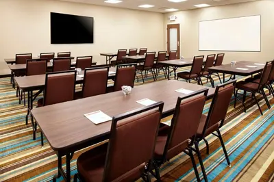 a conference room with tables and chairs and a screen at Hawthorn Extended Stay by Wyndham Saint Clairsville in Saint Clairsville