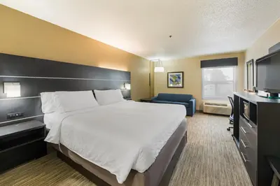 a hotel room with a large bed and a blue chair at Holiday Inn Express London-I-70 by IHG in London