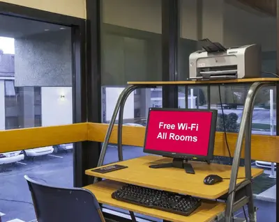 a computer on a desk with a free wiht all rooms sign at Red Roof Inn & Suites Cincinnati North-Mason in Mason
