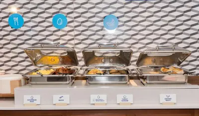 a buffet with several trays of food on a counter at Holiday Inn Express Hotel & Suites Madison by IHG in Madison