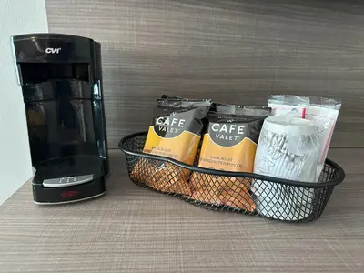a coffee maker and a basket of food next to a coffee mug at Red Roof Inn Cambridge, OH in Cambridge