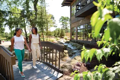 two women walking down a wooden walkway in front of a house at Sawmill Creek by Cedar Point Resorts in Sandusky