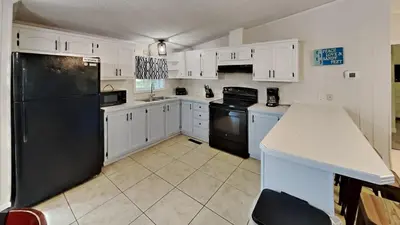 a kitchen with white cabinets and a black refrigerator at Put-in-Bay Island Club #97 in Put-in-Bay