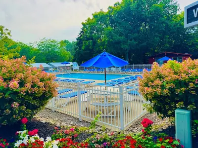 a pool with a blue umbrella and chairs and flowers at Put-in-Bay Island Club #113 in Put-in-Bay