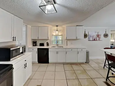 a large kitchen with white cabinets and a table at Put-in-Bay Island Club #66 in Put-in-Bay