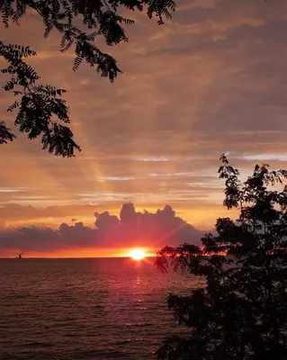 a sunset over the ocean with the sun setting at Put-in-Bay Poolview Condo #3 in Put-in-Bay