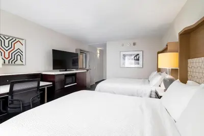 a hotel room with two beds and a desk and a tv at Holiday Inn Weirton-Steubenville Area in Weirton