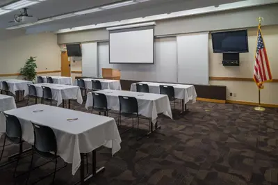 a conference room with white tables and chairs and a screen at LivINN Hotel Cincinnati North/ Sharonville in Sharonville