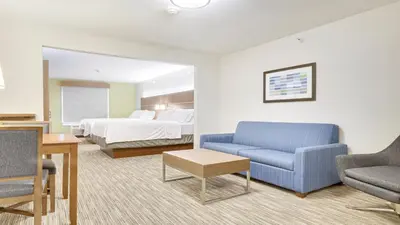 a hotel room with a bed and a couch and a chair at Holiday Inn Express Hotel & Suites Portland by IHG in Portland