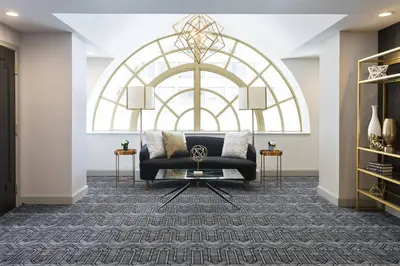 a living room with a black couch and a large window at Hotel LeVeque, Autograph Collection in Columbus
