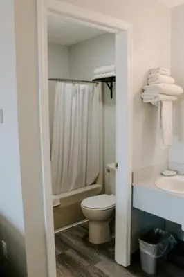 a white bathroom with a toilet and a sink at Berlin Village Inn in Berlin