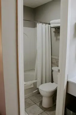 a bathroom with a white toilet and a shower at Berlin Village Inn in Berlin