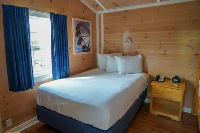 a bedroom with a bed and a window with blue curtains at Cedar Point's Lighthouse Point in Sandusky