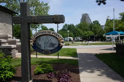 a sign for a park with a roller coaster at Cedar Point's Lighthouse Point in Sandusky