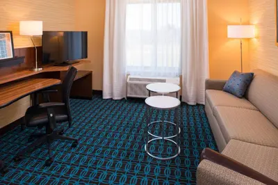 a hotel room with a couch and a desk and a television at Fairfield Inn & Suites by Marriott Akron Stow in Stow