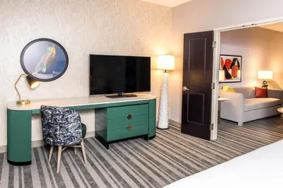 a hotel room with a desk with a television and a couch at Voco The Clair Cincinnati Downtown by IHG in Cincinnati