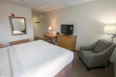 a hotel room with a bed and a chair and a television at Lodging on the Square in Berlin