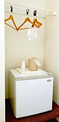a small white refrigerator in a room with a shelf at Lodging on the Square in Berlin