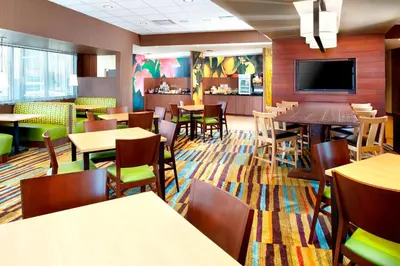 a restaurant with tables and chairs and a flat screen tv at Fairfield by Marriott Inn & Suites Wheeling at The Highlands in Triadelphia