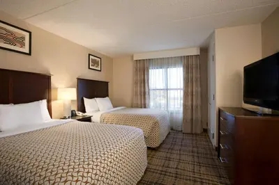 a hotel room with two beds and a flat screen tv at Embassy Suites Cleveland - Beachwood in Beachwood