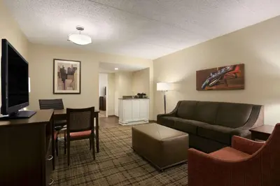 a living room with a couch and a dining room at Embassy Suites Cleveland - Beachwood in Beachwood