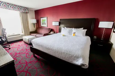 a hotel room with a large bed and a chair at Hilton Garden Inn Columbus/Dublin in Dublin