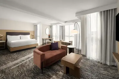 a hotel room with a bed and a couch and a chair at Embassy Suites by Hilton Cincinnati Northeast - Blue Ash in Blue Ash