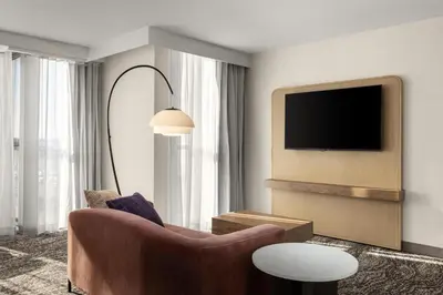 a living room with a chair and a tv at Embassy Suites by Hilton Cincinnati Northeast - Blue Ash in Blue Ash