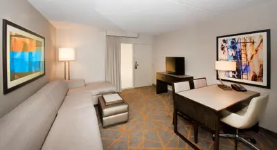 a living room with a couch and a desk in a hotel room at Embassy Suites by Hilton Cincinnati Northeast - Blue Ash in Blue Ash