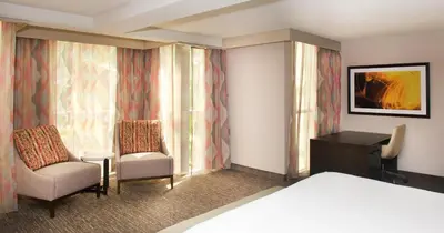 a hotel room with a bed and two chairs and a desk at Embassy Suites by Hilton Cincinnati Northeast - Blue Ash in Blue Ash