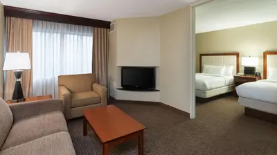 a hotel room with a couch and a bed and a tv at DoubleTree Suites by Hilton Hotel Cincinnati - Blue Ash in Sharonville